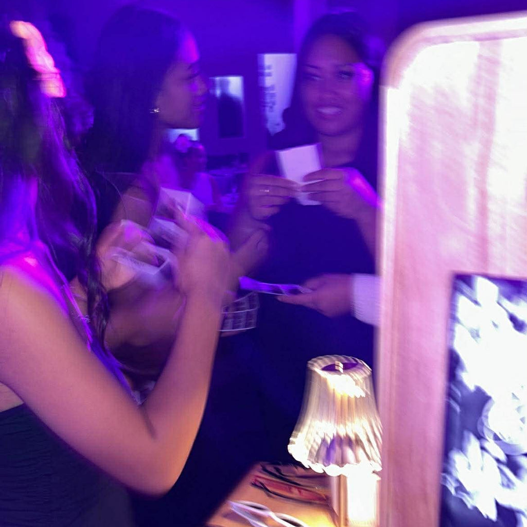 People at a party with a wooden photo booth and lamp.